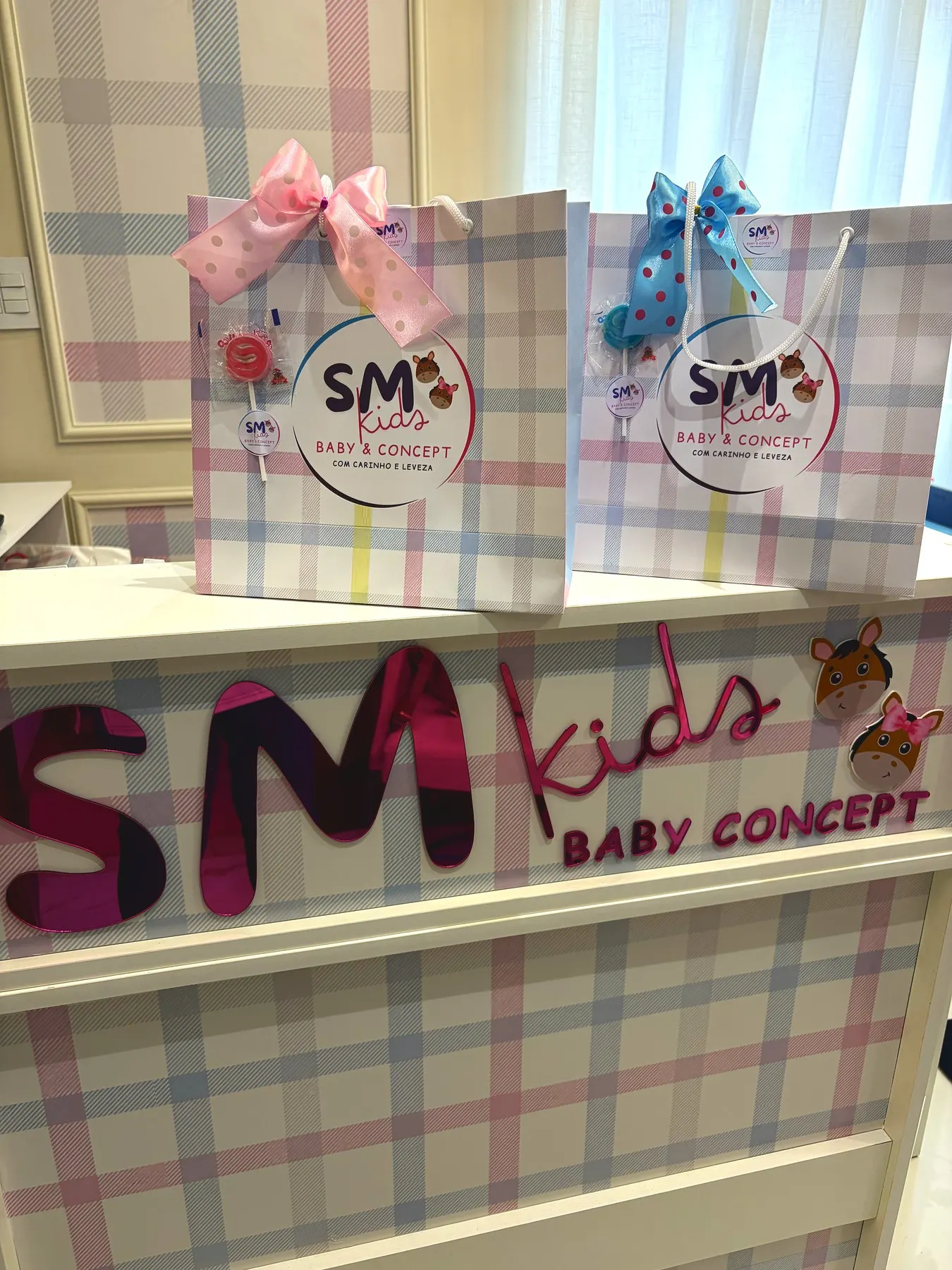 Balcão da SM Kids Baby & Concept em Araçatuba, com o letreiro da marca e as sacolas de presente