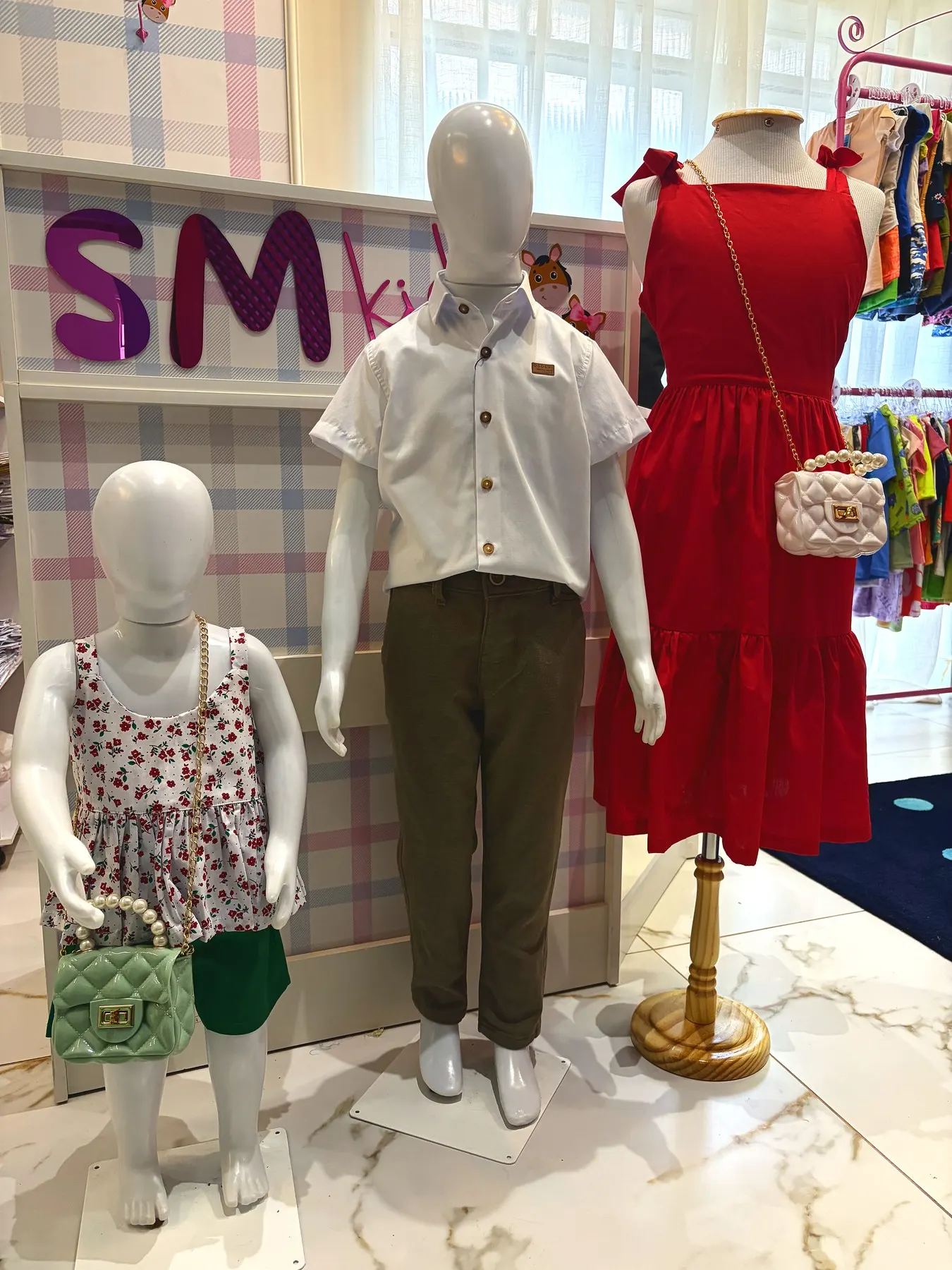 Interior da loja de roupas infantis SM Kids em Araçatuba, com manequins vestidos e o letreiro da marca